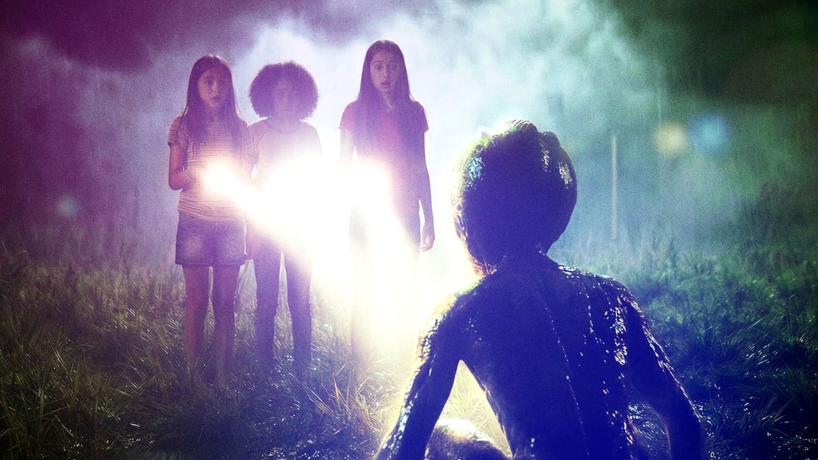 Três meninas diante de uma luz intensa e de uma figura agachada em primeiro plano
